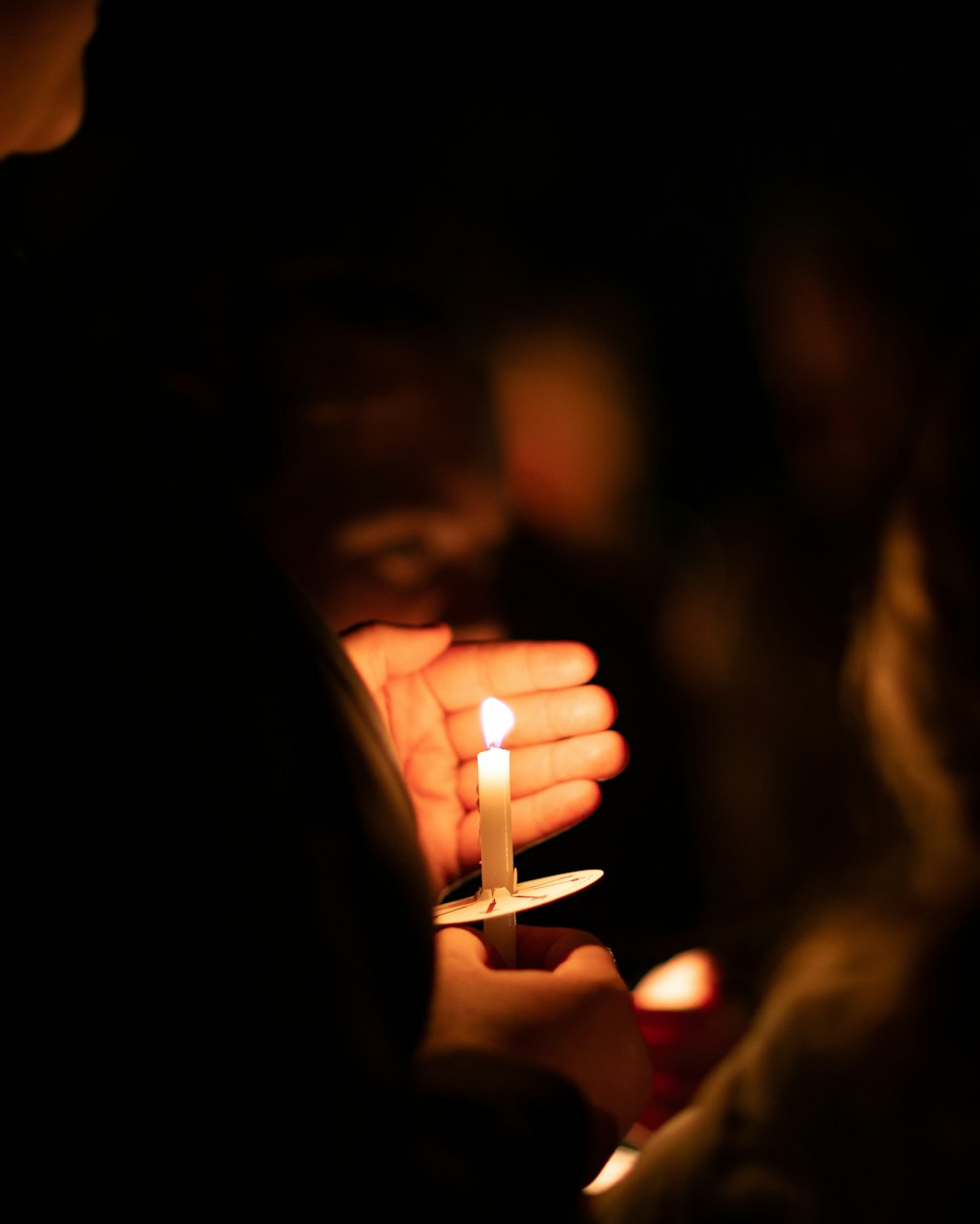 Un visage éclairé par la flamme d'une bougie dans le noir
